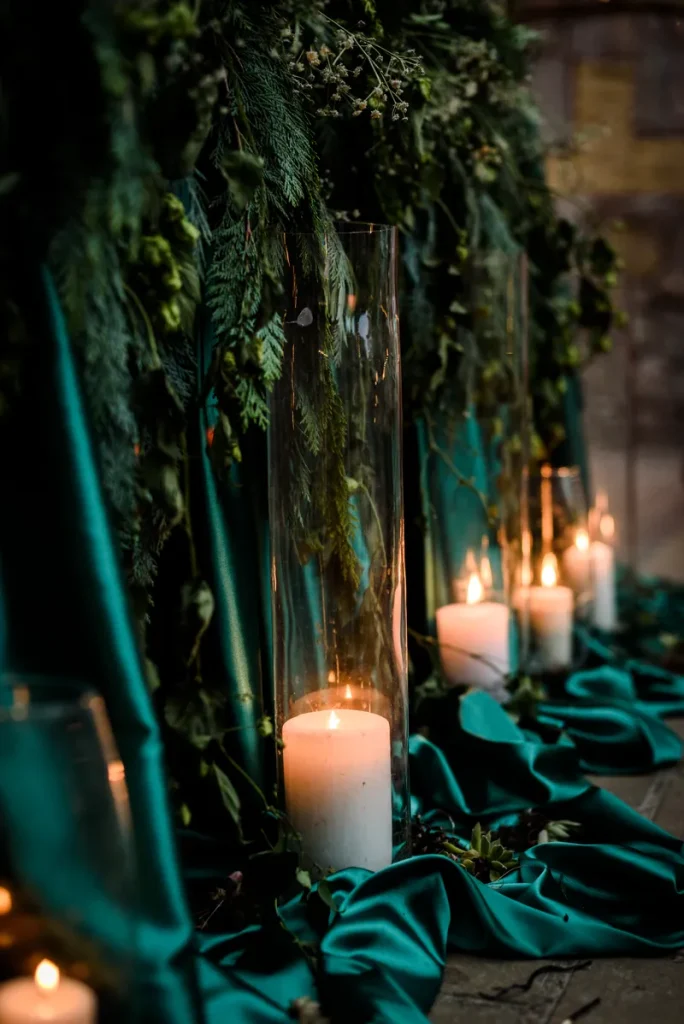 Deep emerald satin and candles decorating the aisle.