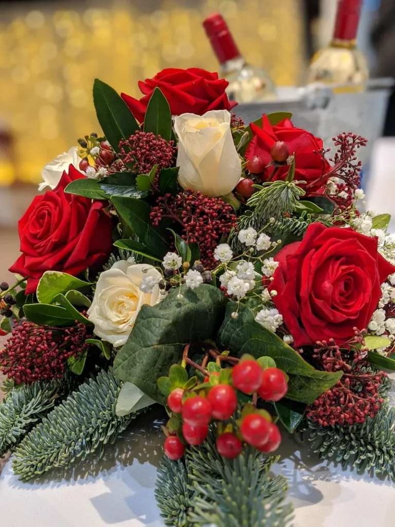 A beautiful bouquet filled with evergreens, roses and holly berries.