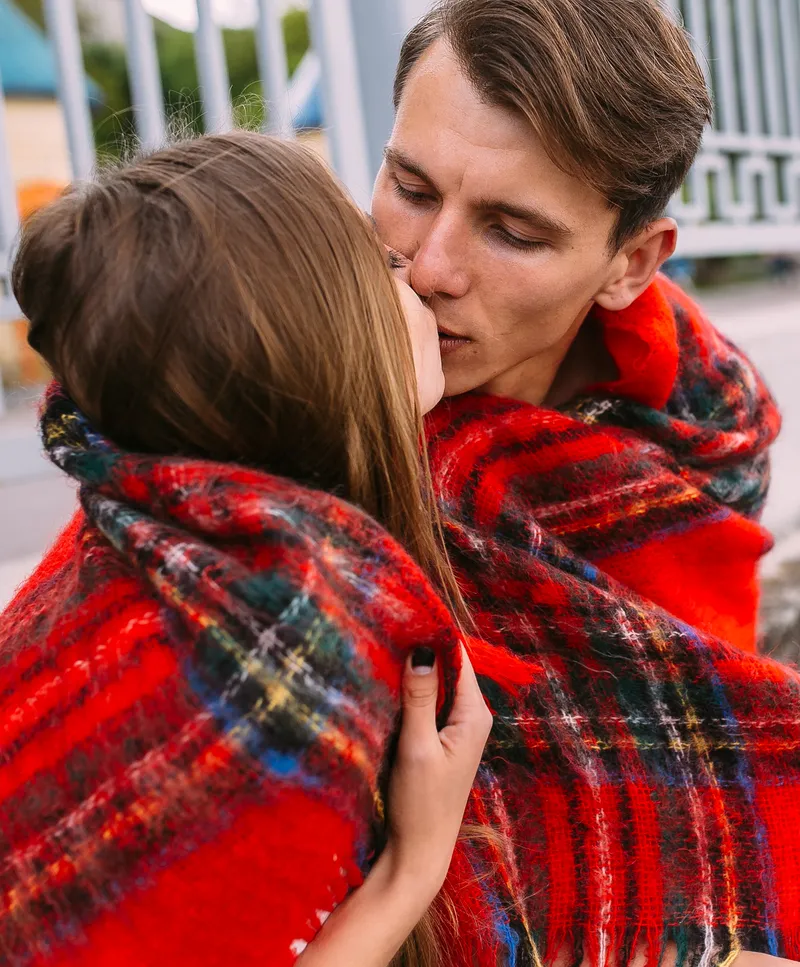 A couple kissing in cozy warm flannel blankets.