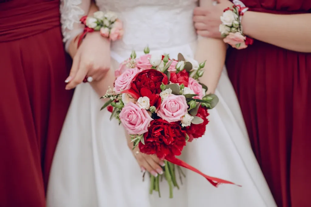 A bride in white with cranberry accents in her bouquet.