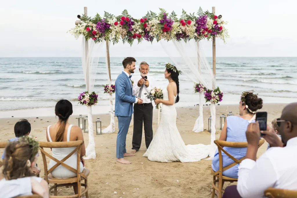 A couple getting married on a beach in a small ceremony.