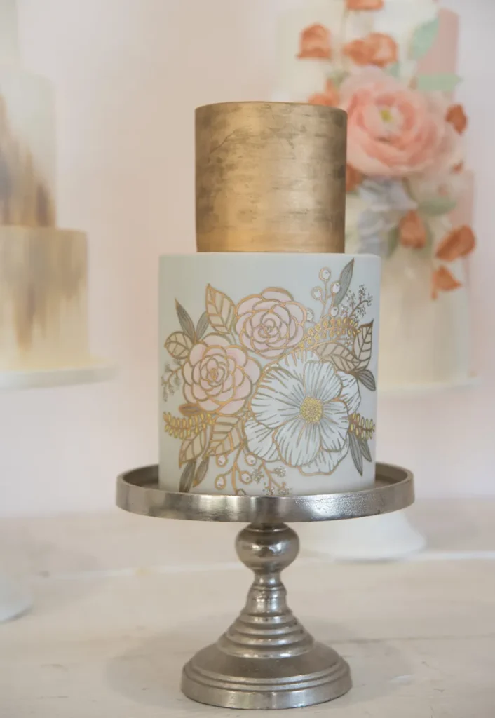 Gold leaf covered cake with some painted on flower decorations.