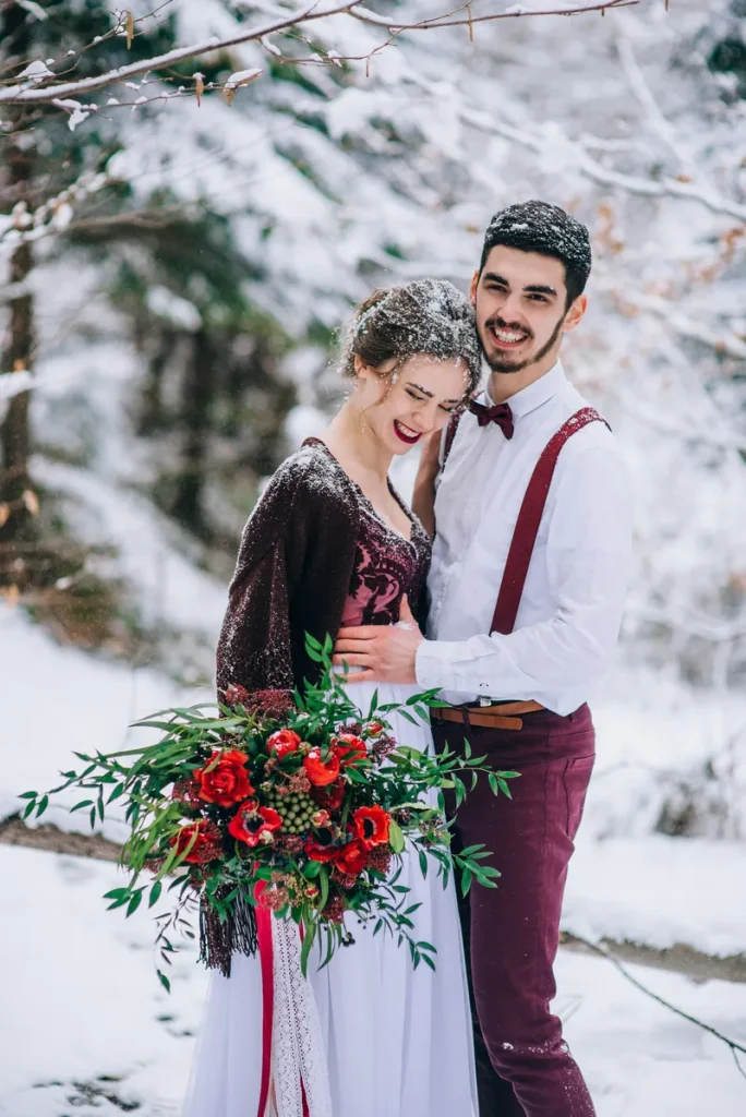 A happy laughing bride and groom dusted with snow outside.