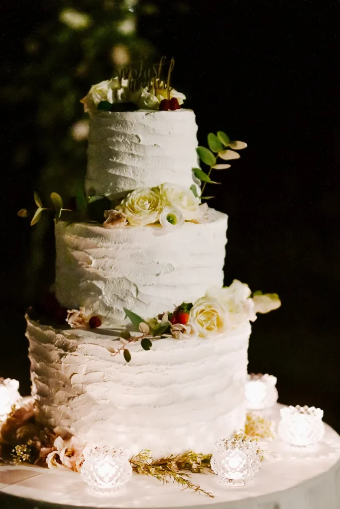 A rustic boho wedding cake with textured icing and fronds of greenery mixed with some choice dried flowers.