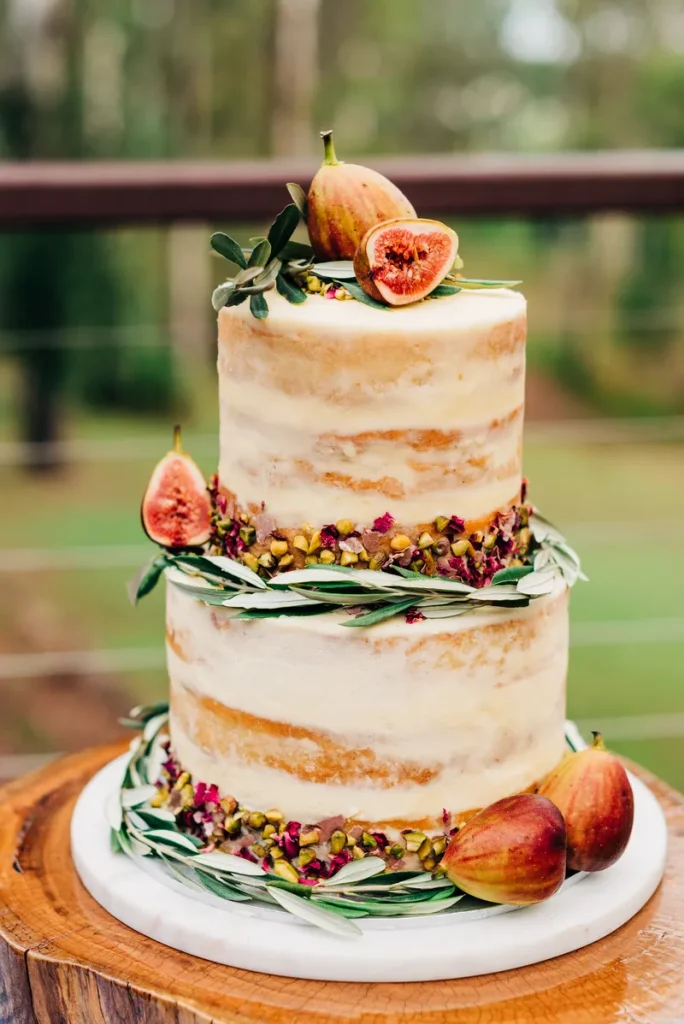 A rustic elegant wedding cake featuring figs and pistachios on a naked cake that balances rustic cozy vibes and elegance.