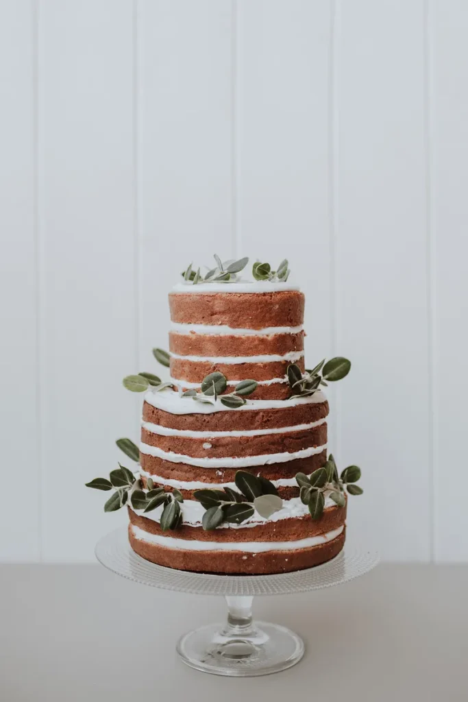 A rustic naked wedding cake without icing on the sides at all, and a simple leaf ring on the different tiers.