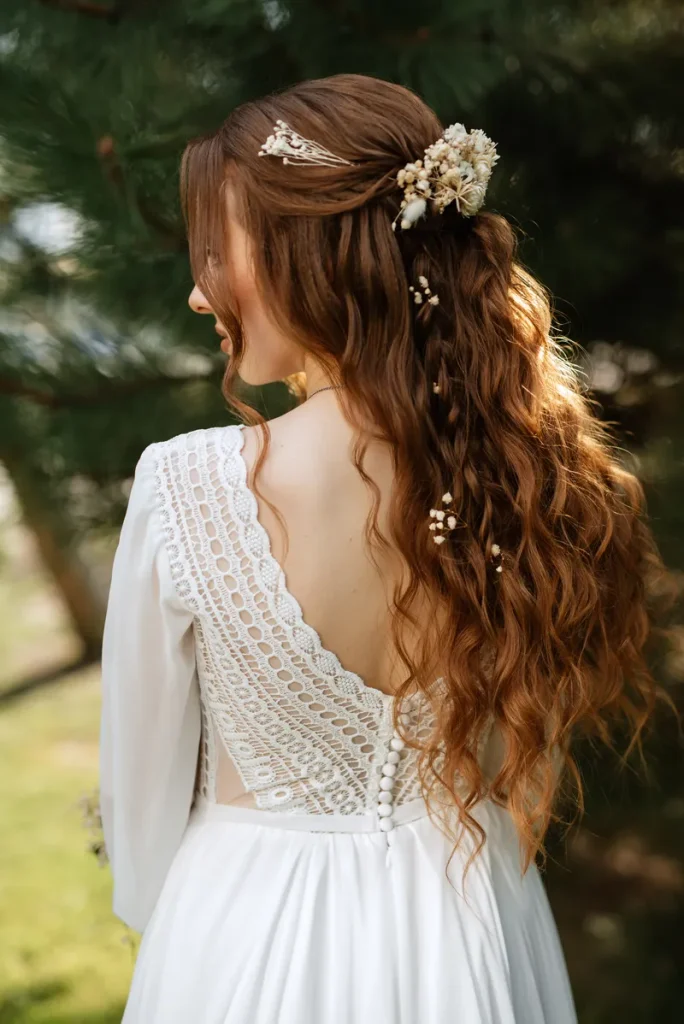 A boho wedding hair half up look featuring flowers and loose waves.