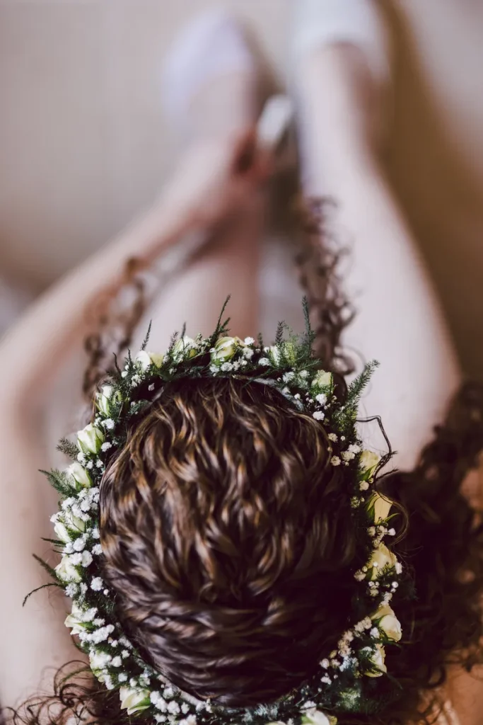 A shot from above of a bride with naturally curly hair, hair framing her face and a flower crown.