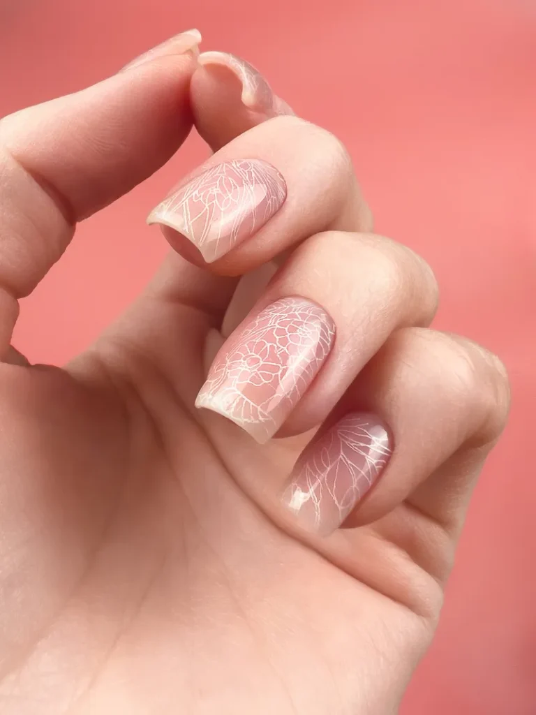 A soft pinky blush nail with a delicate floral linework overlay.