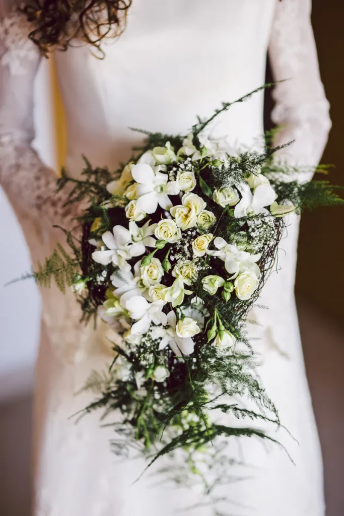 A white cascading bridal bouquet, with ferns trailing down and emphasizing the blooms along the way.