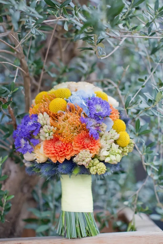 A colorful wedding bouquet for fall that'll make you feel like a happy rainbow on your wedding day amongst all the fall leaves.