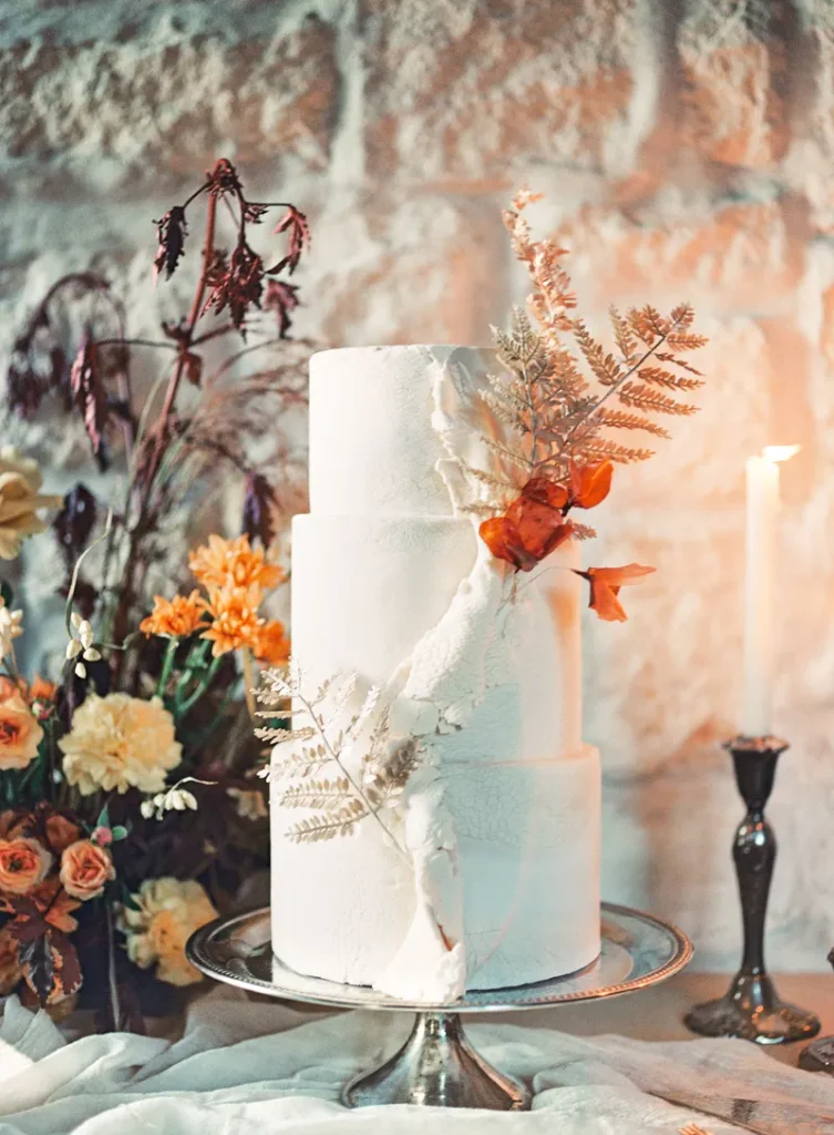 A bohemian wedding cake featuring dried flowers and fern fronds.