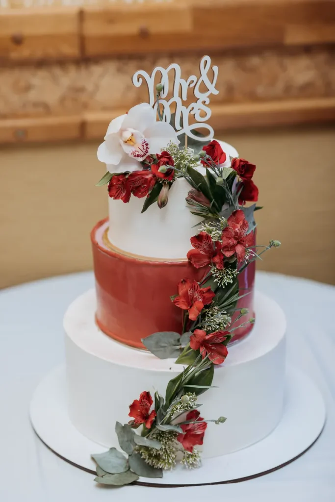 A multi-tiered fall wedding cake with a burgundy center tier.