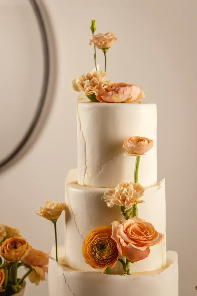 An elegant fall wedding cake featuring some white chocolate shards and toffee roses as decoration.