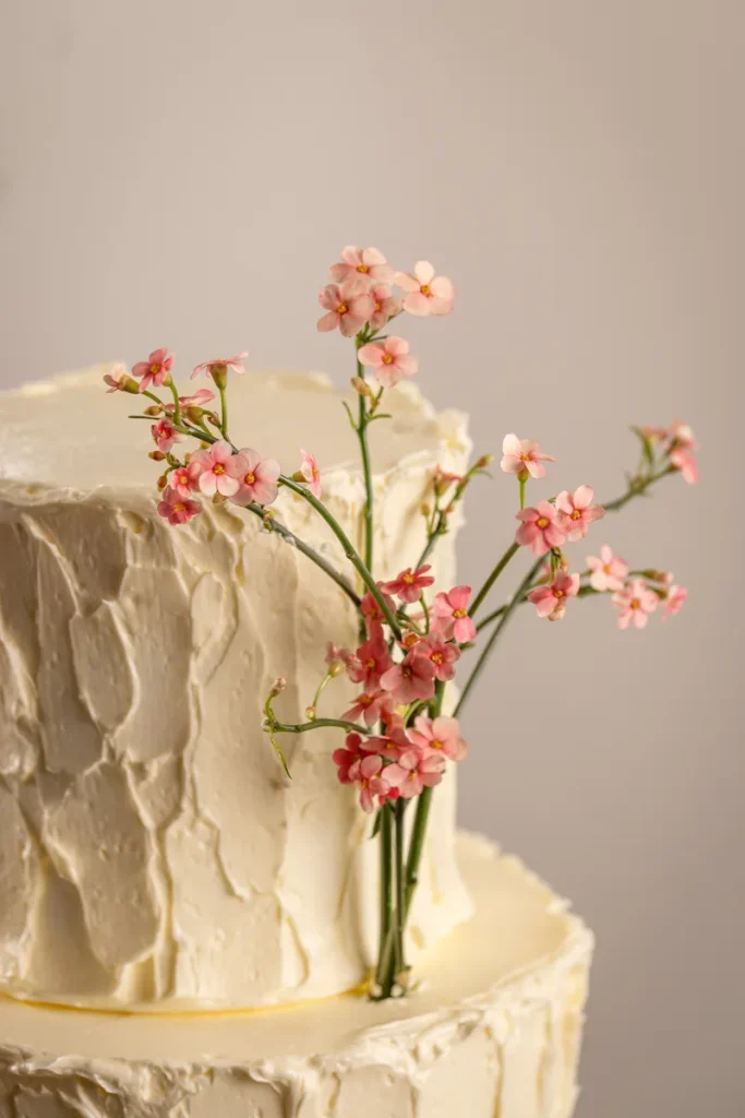 A look at a simple fall wedding cake featuring textured buttercream and a single flower sprig.