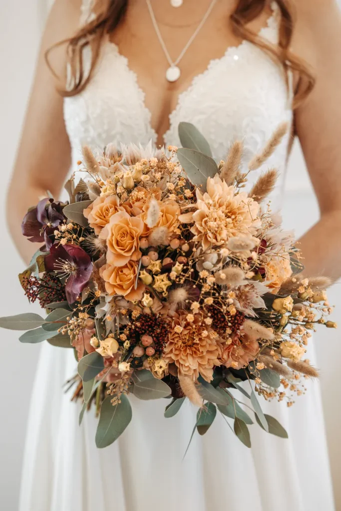 A picture of a beautiful bridal bouquet including dried grass and seed pods you can use as an example for your fall wedding flowers.