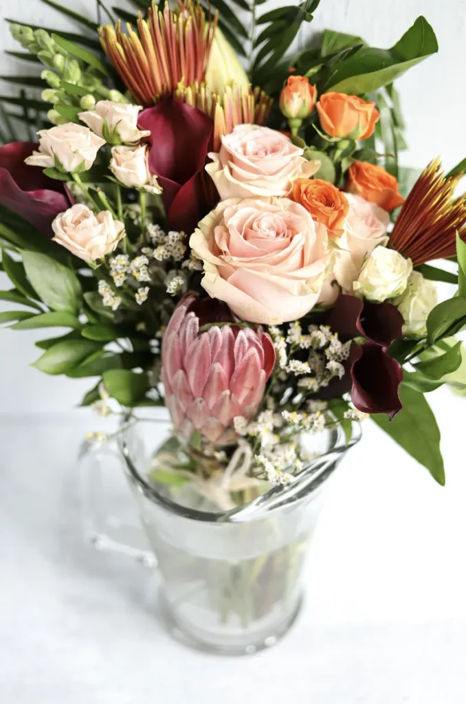 A burgundy and blush fall wedding centerpiece full of beautiful florals with a little greenery to make the flowers pop.