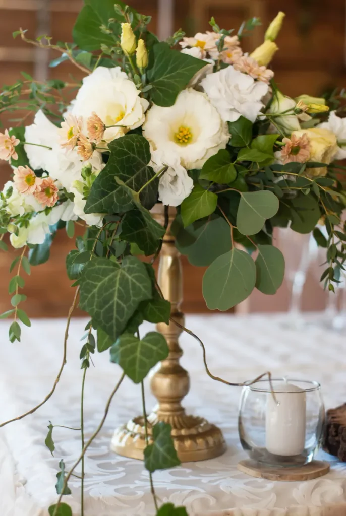 A fall wedding centerpiece of beautiful florals on a gold stand.