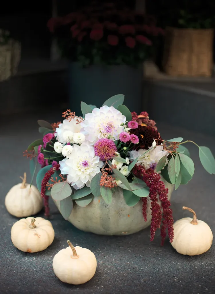 A fall wedding centerpiece featuring pumpkins and greenery such as eucalyptus and some beautiful flowers. 